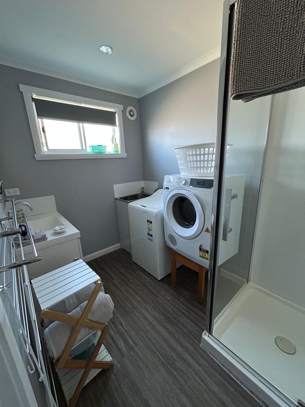 Bathroom with shower, washing machine and dryer in Apartment Two